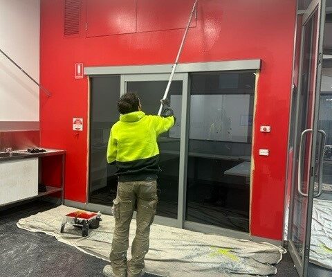 Man painting a wall red.