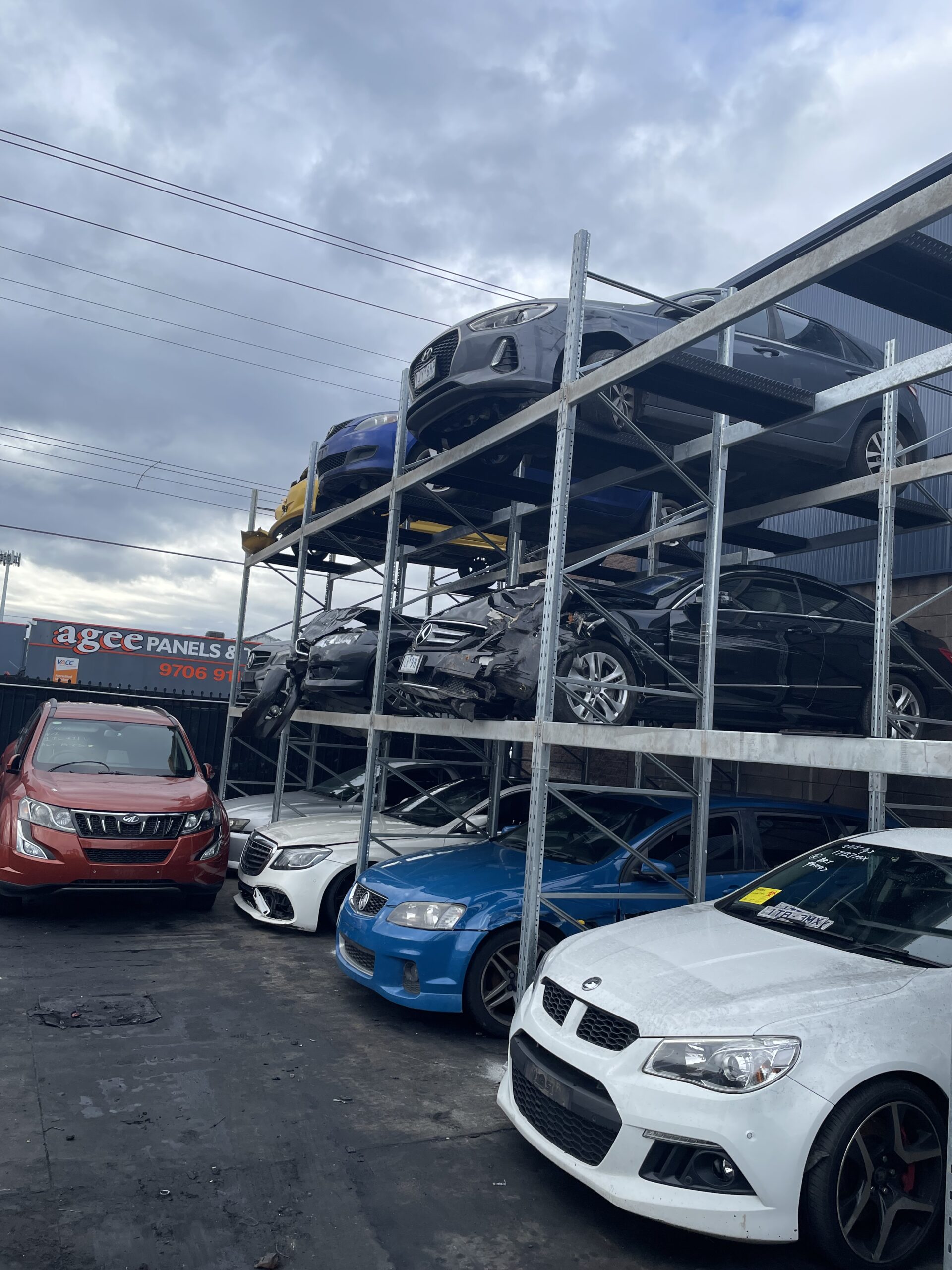 Car yard with many damaged cars. Custom car racking is being used to stack the cars three high.