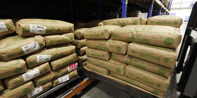 Forklift loading a pallet of sodium chloride bags on push back pallet racking.