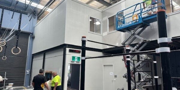 Scissor lift in a warehouse working on the exterior of a mezzanine office.