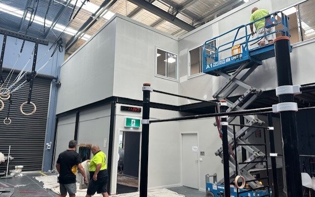 Scissor lift in a warehouse working on the exterior of a mezzanine office.