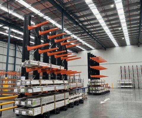 Two sets of cantilever racking in a warehouse. The cantilever racking is holding long spans of a material.